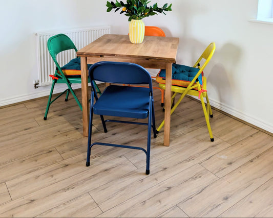 Dining area with a wooden table and colorful chairs on a wooden floor.